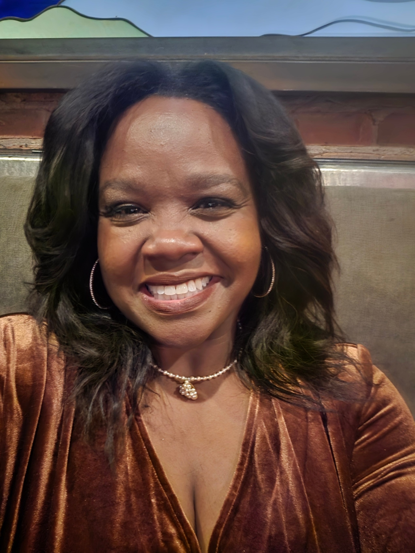 Portrait of Temeka Hayes smiling in front of an exposed brick wall
